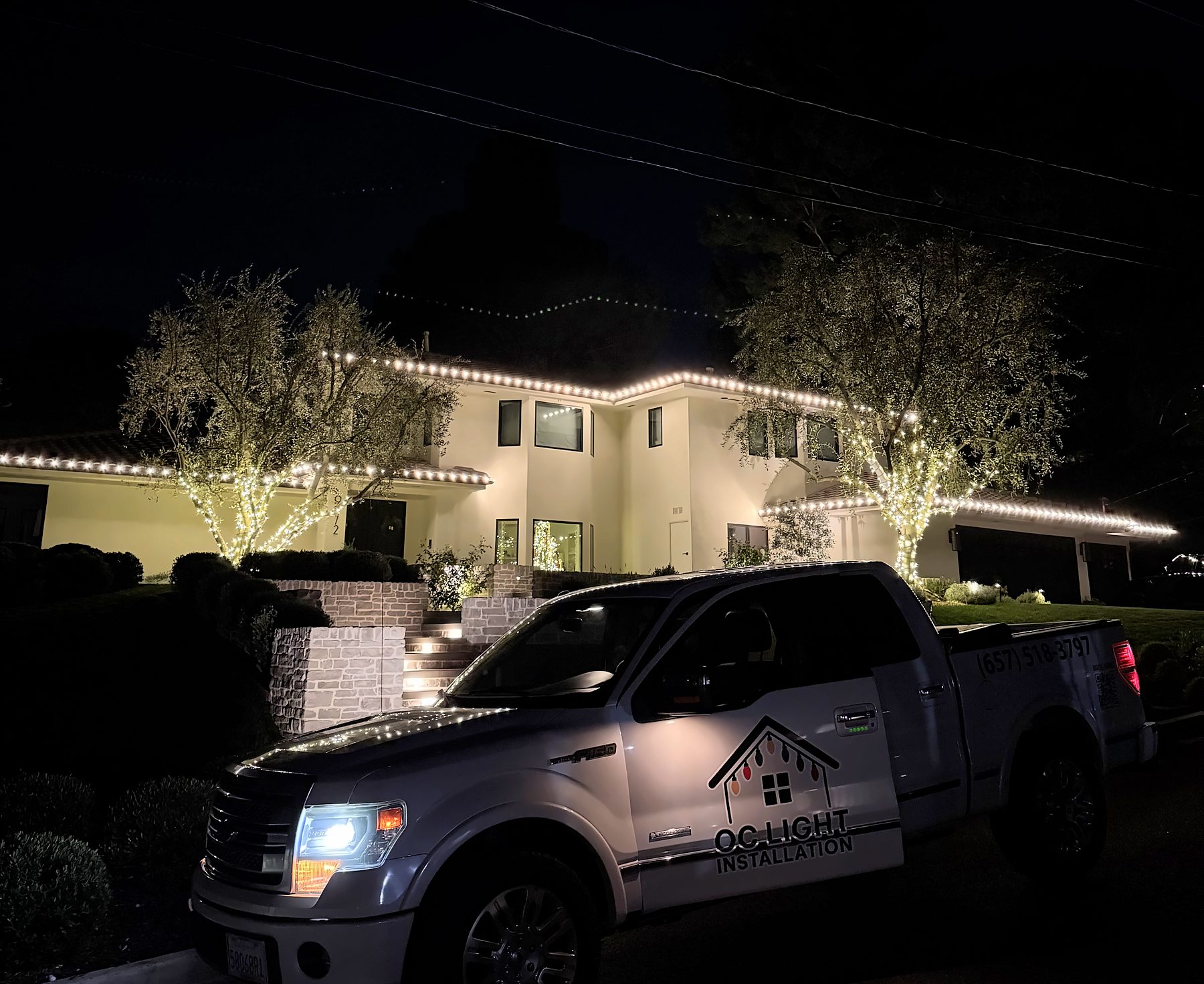 Our truck at a finished two-story install: warm white roofline and wrapped trees